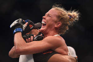 女MMA拳手與對手緊緊擁抱慶祝勝利。 — 喜悅 壁紙