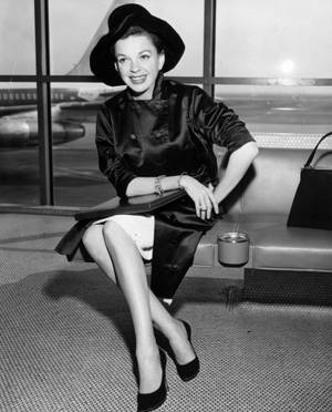 1950年代時尚女性在機場航廈窗邊微笑，窗外有飛機。 — 女演員 壁紙