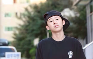戴黑色鴨舌帽和穿T恤的年輕人站在戶外，表情沉思。 — 你的名字 GIF 壁紙