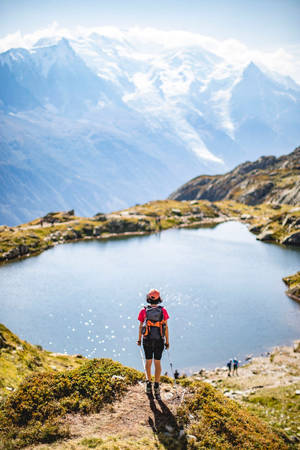 健行者持杖俯瞰山間湖泊，晴朗天氣 — 登山 壁紙