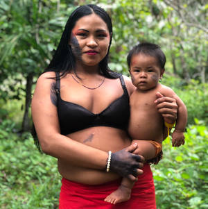 一位帶有傳統標記的母親在森林中抱著她的嬰兒。 — 亞馬遜 壁紙