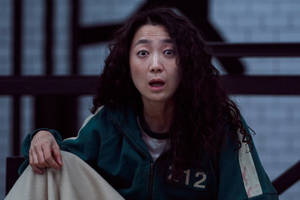 穿著綠色編號外套的女性睜大眼睛顯得震驚。 — 067 魷魚遊戲 壁紙