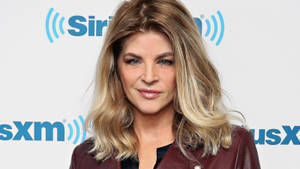 在SiriusXM活動中，身穿栗色外套的女性對著鏡頭微笑。 — 好萊塢 壁紙