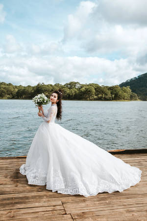 新娘穿白色蕾絲婚紗在湖邊碼頭捧花束 — 婚紗 壁紙