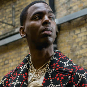 男士身穿Gucci外套和金色首飾，背景為磚牆。 — Young Dolph 壁紙