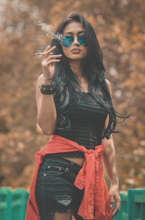一位戴太陽眼鏡和紅色外套的女性在秋天戶外抽煙。 — 抽菸 壁紙