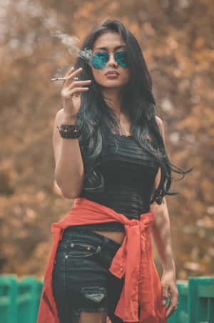 一位戴太陽眼鏡和紅色外套的女性在戶外秋天抽煙。 — 抽菸 壁紙