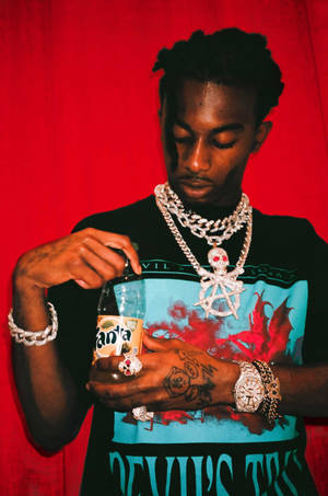 有刺青和鑽石首飾的男士在紅色背景下打開芬達瓶。 — Playboi carti 大頭貼 壁紙