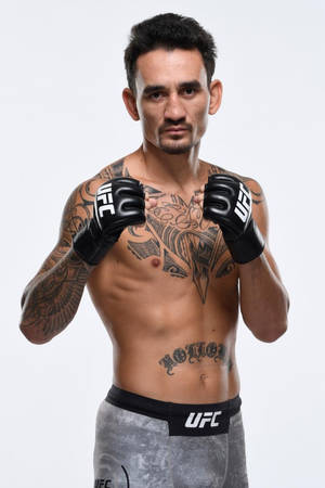 一位有刺青的男性UFC拳手，戴著手套和灰色短褲，擺出戰鬥姿勢。 — 運動 壁紙