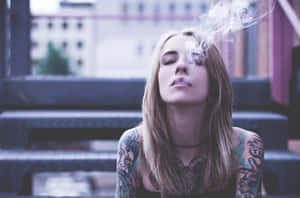 有刺青的女性坐在城市階梯上，閉著眼睛呼出煙霧。 — 抽菸 壁紙