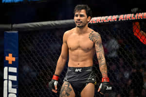 有刺青的MMA拳手站在UFC八角籠內，穿著黑色短褲和手套。 — 運動 壁紙