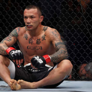 一位有刺青的MMA選手在比賽後坐在八角籠地上。 — 終極格鬥冠軍賽 壁紙
