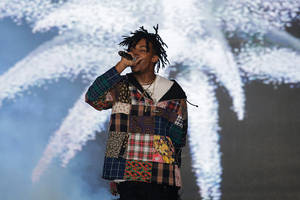 穿著拼布外套的饒舌歌手在抽象背景前表演。 — Playboi carti 大頭貼 壁紙