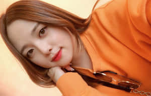 身穿橙色毛衣的年輕女子手托下巴，附近有太陽眼鏡。 — 可愛 壁紙