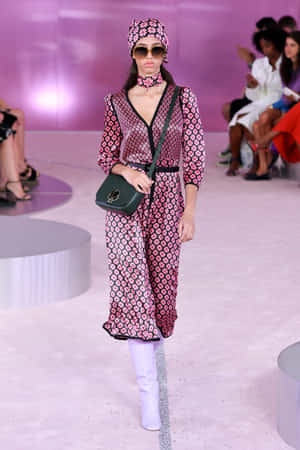 模特兒穿著花卉連衣裙和白色靴子在時裝秀上走秀。 — Kate spade 壁紙