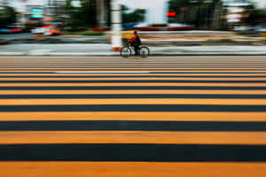 自行車騎士正在移動中穿過條紋行人穿越道 — 橘色 壁紙