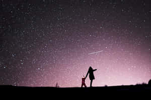 母親和孩子在流星劃過的星空下牽手。 — 星星 壁紙