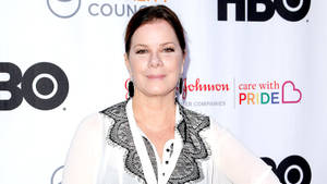 在HBO Pride活動中穿著白色蕾絲襯衫的女性對著鏡頭微笑 — 好萊塢 壁紙