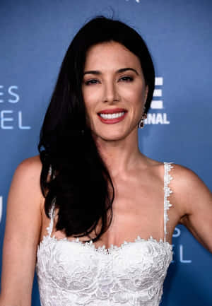 穿著白色蕾絲連衣裙的女性在藍色背景的活動中微笑。 — 克莉絲汀·史都華 壁紙
