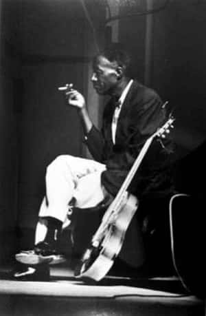 爵士樂手在昏暗的錄音室燈光下手持香煙和低音提琴。 — 音樂 壁紙