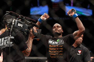 UFC拳手在八角籠內高舉拳頭慶祝勝利。 — 終極格鬥冠軍賽 壁紙