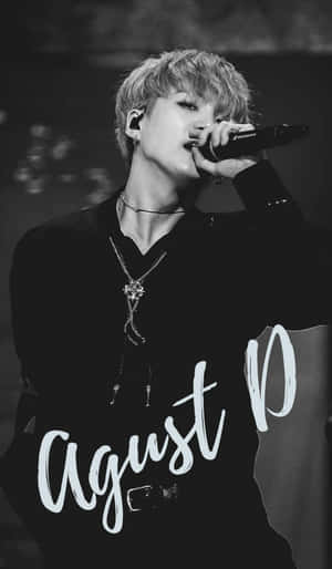 男K-pop歌手在舞台上表演，手持麥克風，佩戴多層項鍊。 — 阿德里安·阿格雷斯特 壁紙