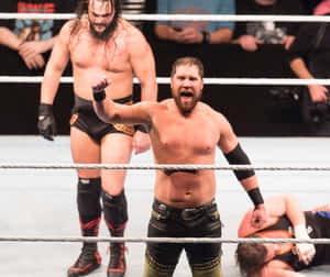 摔角手在擂台上高舉拳頭慶祝勝利，對手躺在地上。 — WWE GIF 壁紙