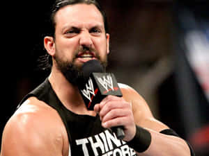 摔角手穿著黑色背心對著 WWE 麥克風大喊。 — 摔角 壁紙