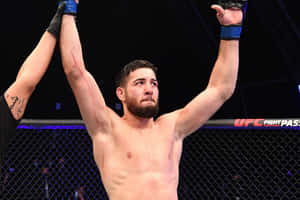 UFC鬥士在八角籠內高舉雙臂慶祝勝利。 — 運動 壁紙