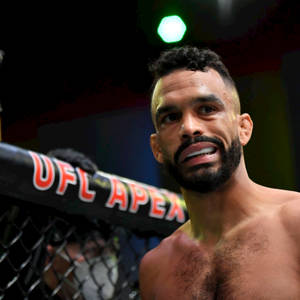 一位赤裸上身的MMA拳手在場館燈光下於UFC Apex八角籠內微笑。 — 運動 壁紙