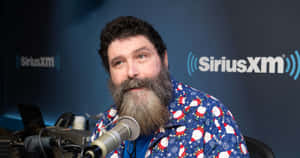 留鬍鬚的男子穿著聖誕襯衫在SiriusXM錄音室對著麥克風說話。 — WWE GIF 壁紙