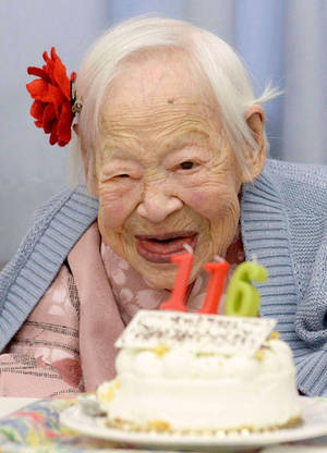 一位老婦人微笑著吹熄116歲生日蛋糕上的蠟燭。 — 生日快樂蛋糕 壁紙