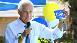 在戶外集會中，男子手持Crist for Governor競選標語牌。 — 寒冷 壁紙
