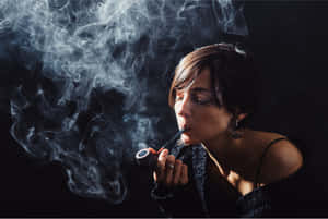 一位女性在深色背景前抽煙斗，煙霧旋轉。 — 抽菸 壁紙
