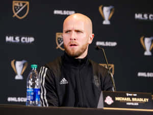 禿頭鬍鬚男穿黑色Adidas外套在MLS Cup新聞發布會。 — 運動 壁紙