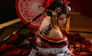 一位穿著傳統日本連衣裙的女性，帶有花卉紋身和紅色配飾，被花瓣環繞。 — 刺青 壁紙