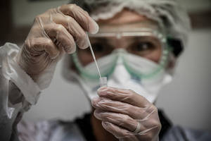 穿著防護裝備的科學家在實驗室中處理試管。 — 醫療 壁紙