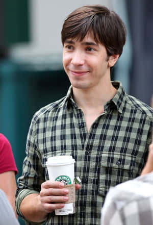 年輕男士手持Starbucks咖啡杯，在戶外微笑。