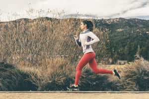 一位女性在戶外靠近乾草和山的泥路上跑步。 — Running 壁紙
