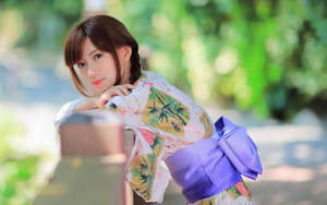 年輕女子穿著花卉和服靠在花園木欄杆上 — 日本 壁紙