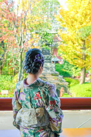 穿著花卉和服的女士從木陽台透過秋樹觀看寺廟。 — 日式 壁紙
