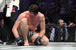 一位被擊敗的MMA選手在比賽後跪在八角籠內。 — 運動 壁紙