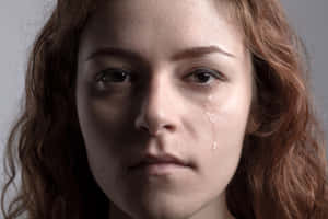 一位紅髮女性流下一滴淚水順著臉頰。 — 孤獨悲傷 壁紙
