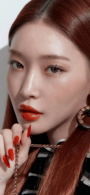 紅髮紅唇的女性在嘴唇附近拿著一條鏈條。 — 金範 壁紙