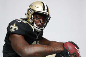 身穿聖徒隊球衣的美式足球員手持足球，紋身清晰可見 — Alvin Kamara 壁紙