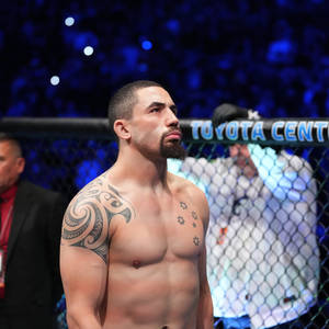 一位帶有紋身的MMA戰士在比賽期間站在籠內。 — 運動 壁紙