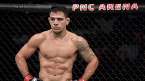 一位專注的 MMA 鬥士在 PNC 體育館的籠子裡，帶有刺青和閃閃發光的汗水。 — 極限運動 壁紙