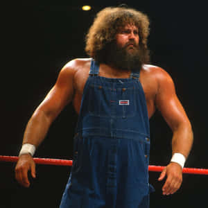 身穿藍色工裝褲的摔角手站在帶有紅色繩索的摔角台上。 — WWE GIF 壁紙
