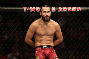 一位赤裸上身的MMA戰士穿著紅色短褲，站在T-Mobile Arena的格鬥籠內。 — 運動 壁紙