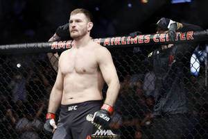 MMA拳手穿著黑色短褲和手套，站在八角籠內。 — 運動 壁紙